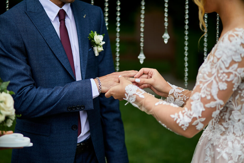 Braut steckt Bräutigam Ring an Hochzeit