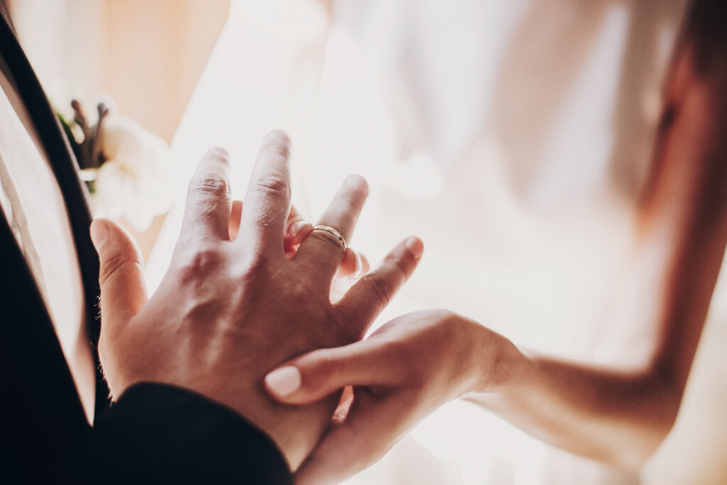 Braut steckt Bräutigam Trauring an Hochzeit