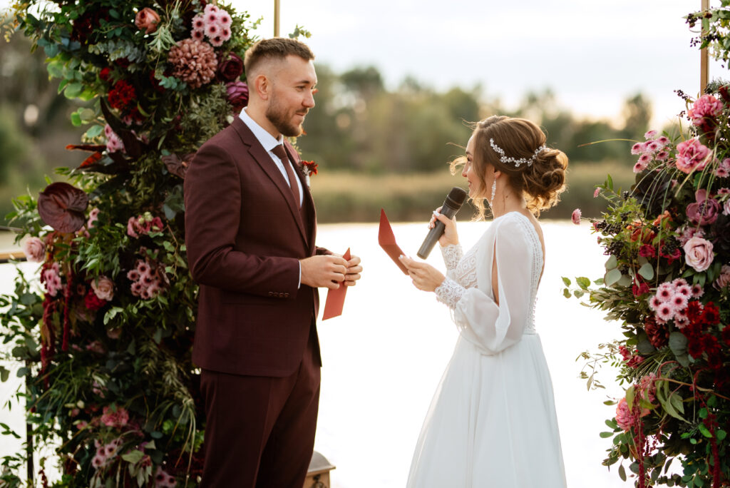 Brautpaar gibt sich Eheversprechen bei herbstlicher Hochzeit am Wasser