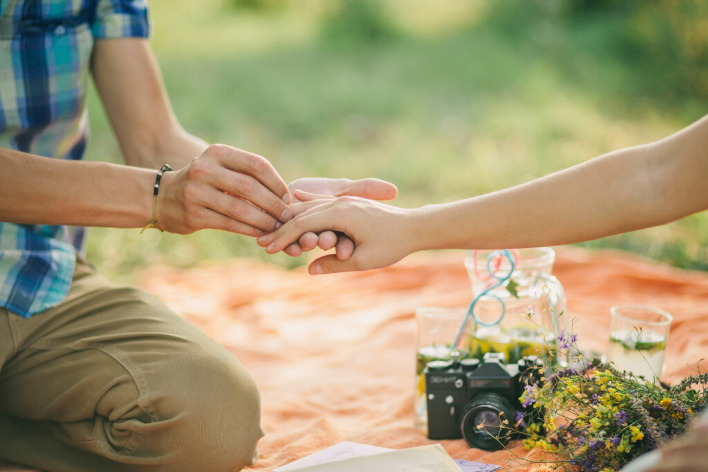Mann macht einer Frau einen Heiratsantrag beim picknicken