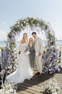 Die Hochzeitsplanerin Sophia von Aspern mit einem Brautpaar vor einem Traubogen voller Blumen, bei einer Hochzeit in Hamburg.